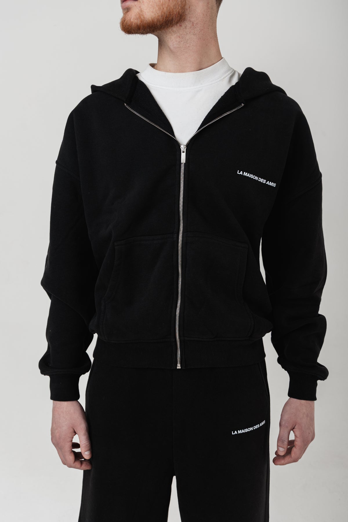 Close-up of the high-quality fabric and subtle branding on the black zip-up lounge suit, designed for everyday wear